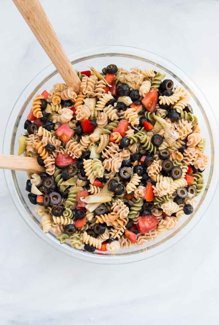 Overhead photograph of a glass bowl containing easy pasta salad recipe with fresh veggies and italian dressing.