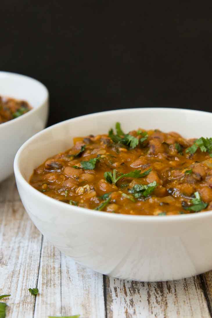 A side photograph of vegan black eyed peas recipe served in a white round bowl, garnished with fresh cilantro.