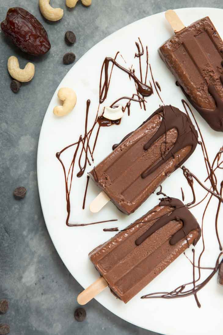 Overhead view of chocolate covered fudgesicles with dates and cashews in the background.