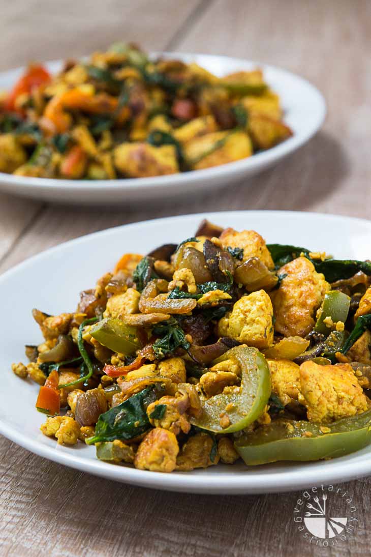 A front view photograph of two white platse containing curried tofu scramble, one is out of focus in the background.