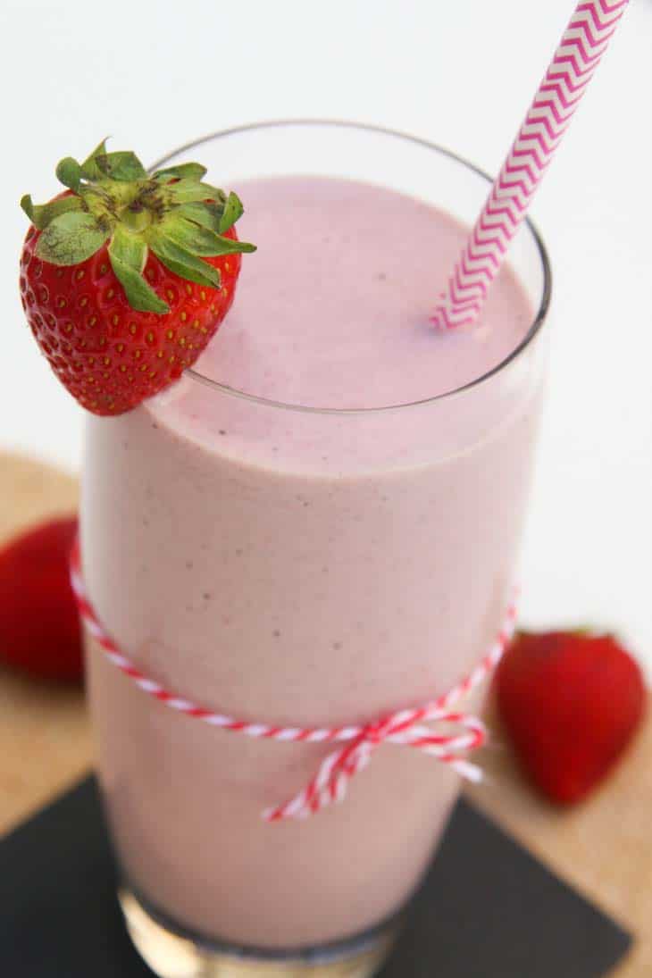 Close-up of strawberry milkshake recipe with a pink string tied and fresh strawberries.