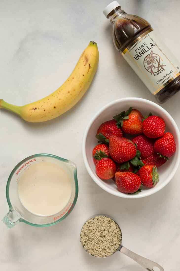 Overhead photograph of 5 ingredients used to make strawberry milkshake recipe.