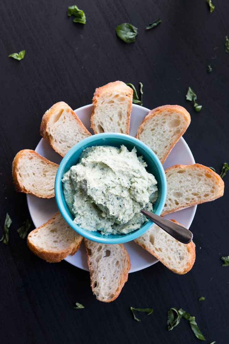 Overhead photograph of vegan tofu ricotta. It's plated in a light blue bowl and served with slices of french bread. 