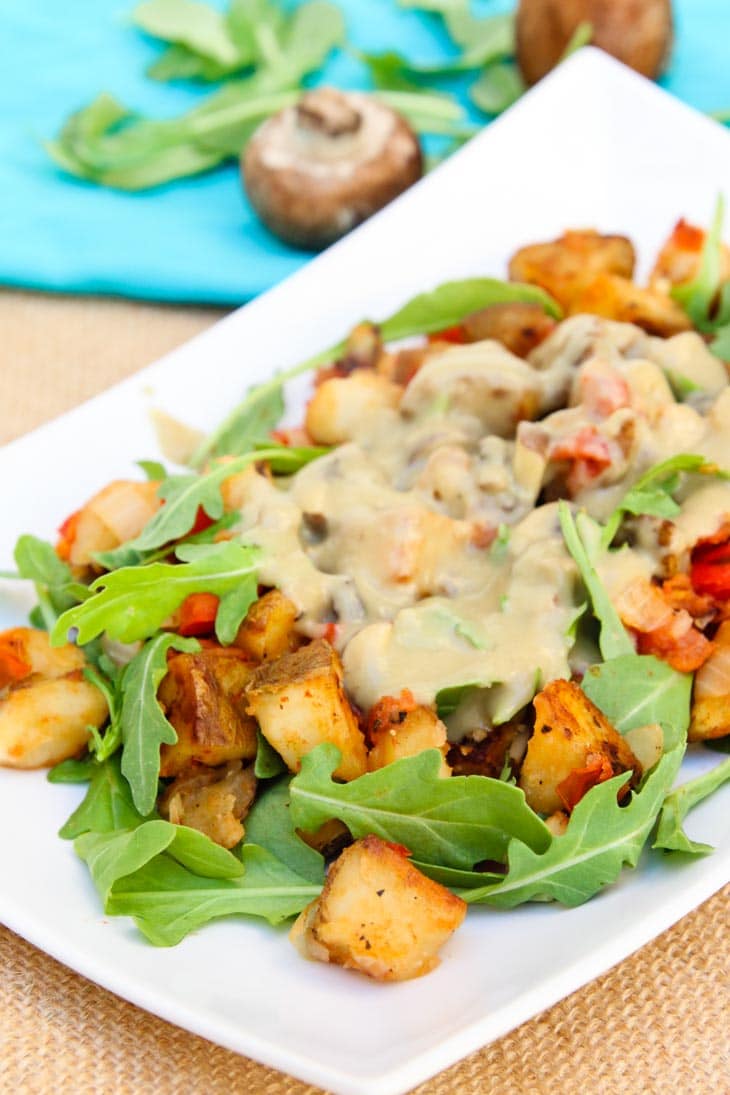 A vegan breakfast bowl made with loaded potatoes and gravy on a white plate