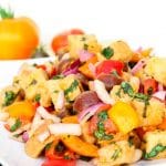 A side shot of a tuscan panzanella salad with white beans on a white plate