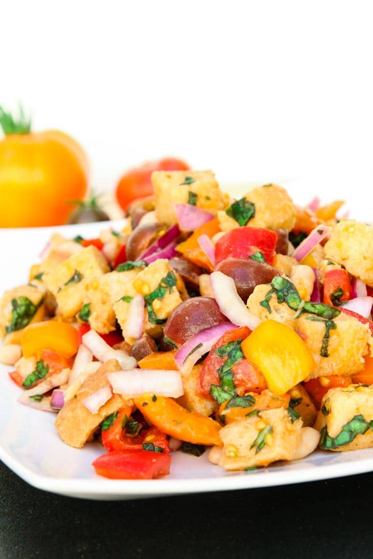 A side shot of a tuscan panzanella salad with white beans on a white plate