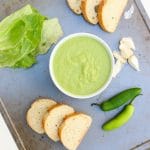 An overhead shot of spicy green peruvian sauce on a tray with slices of bread at the side