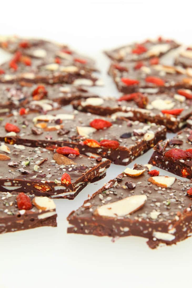 A close up of dark chocolate bark broken into pieces on a white surface