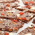 A close up of dark chocolate bark topped with fried berries, nuts and seeds