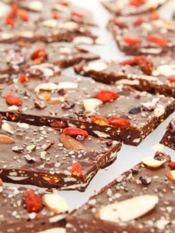 A close up of dark chocolate bark topped with fried berries, nuts and seeds