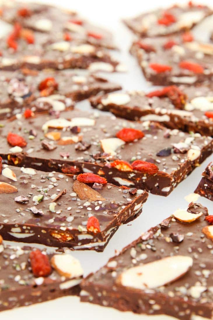 A close up of dark chocolate bark topped with fried berries, nuts and seeds