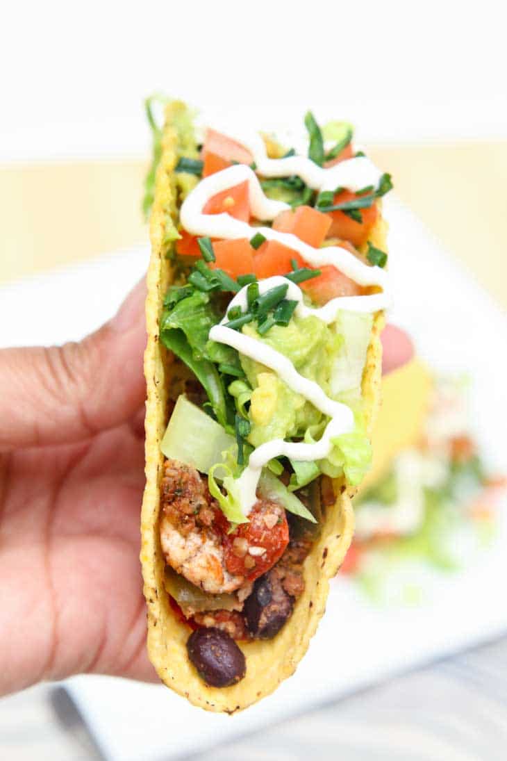 A side close-up photograph of a person holding a vegan tofu taco.