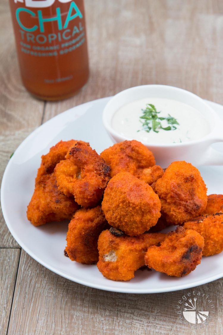 Buffalo Cauliflower Bites on a white plate with a side of vegan cucumber ranch.