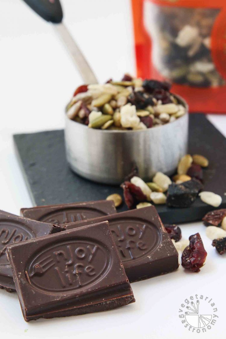 Closeup portrait image of the ingredients that go into my No-Bake Chewy Chocolate Date Cookies. There's Enjoy Life allergen-friendly Boom Choco Boom Dark Chocolate Bars, and their Beach Bash Seed and Dried Fruit mix. They are vegan, gluten-free, and eggless. 