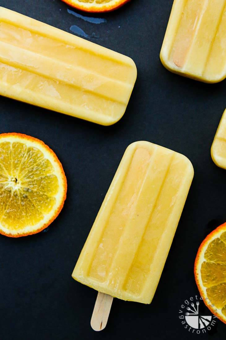 An overhead photograph of orange julius popsicles with slices of orange around the sides.