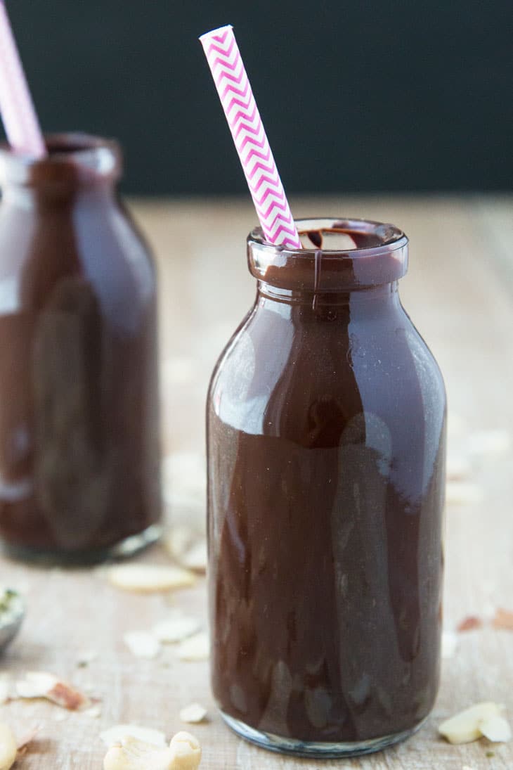 Photograph of a milk bottle filled with vegan chocolate milk, containing a pink designed straw. 