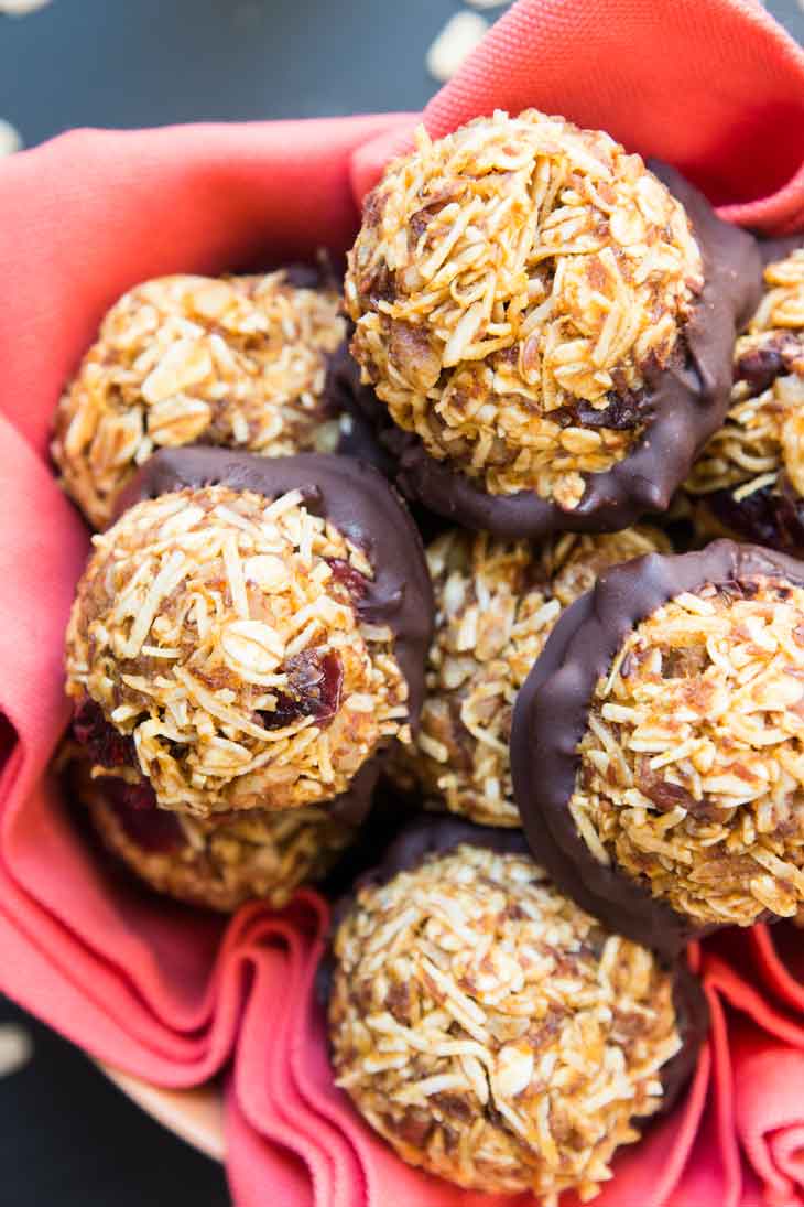 An overhead closeup photograph of no-bake vegan pumpkin cookies dipped in chocolate and sitting on an orange napkin. 