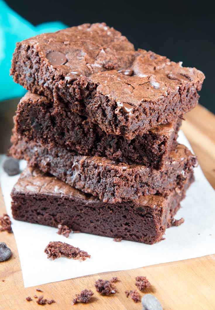A close-up photograph of richa's vegan brownie recipe stalked together and sitting on parchment paper. 
