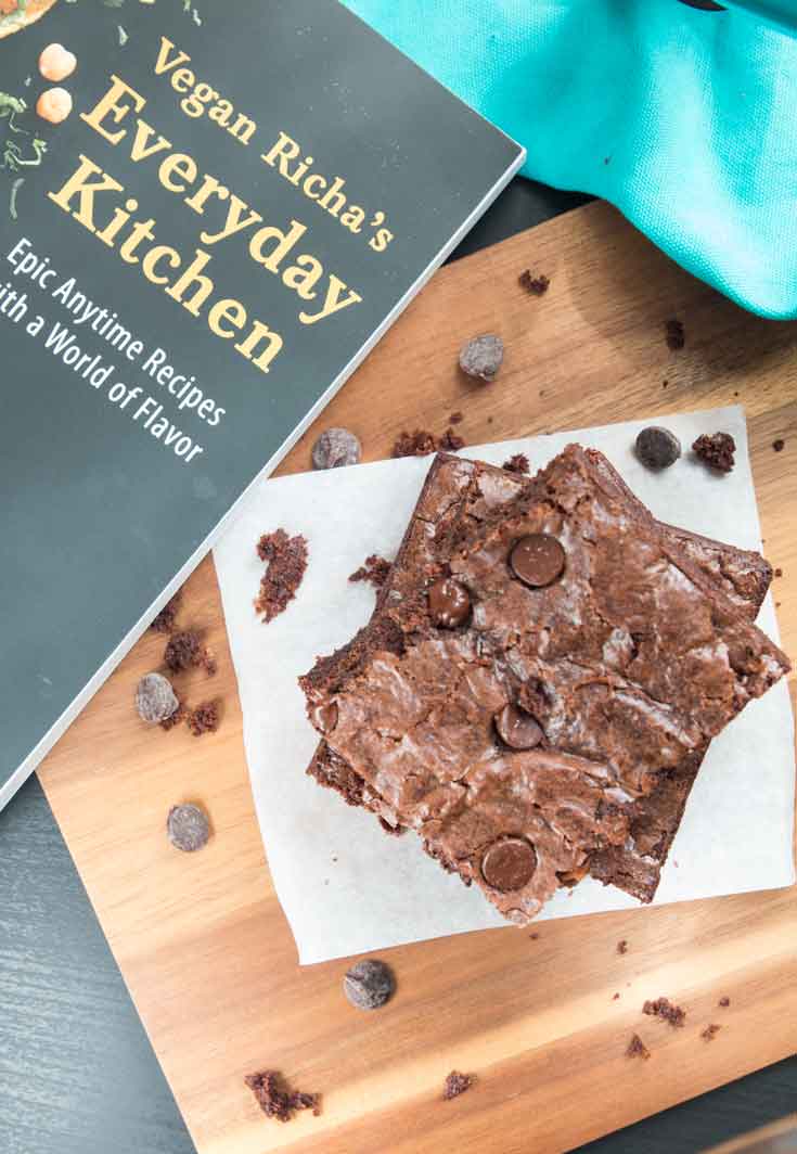 An overhead photograph of a stack of richa's vegan brownie recipe sitting next to 'vegan richa's everyday kitchen' cookbook. 