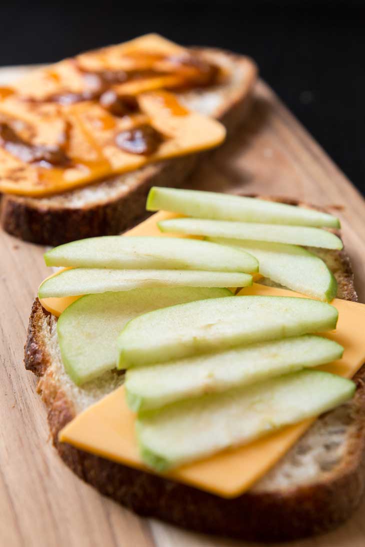 A side view closeup of an open face vegan grilled cheese with green apples, pumpkin butter, and cheese!