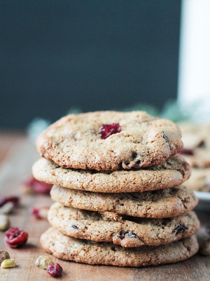 A stack of cranberry pistachio cookies with cranberries and pistachios as garnish. 