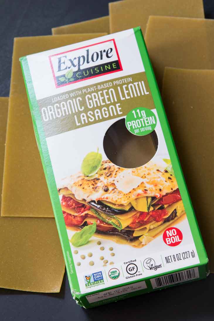 A box of explore cusine green lentil lasagna sheets with some sheets laying under.