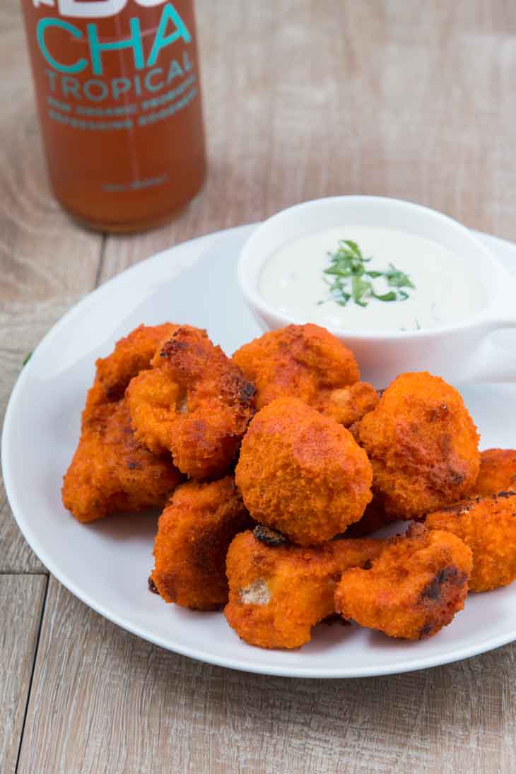 Number one best vegan meal on VG. Buffalo cauliflower bites on a white round plate served with vegan ranch.