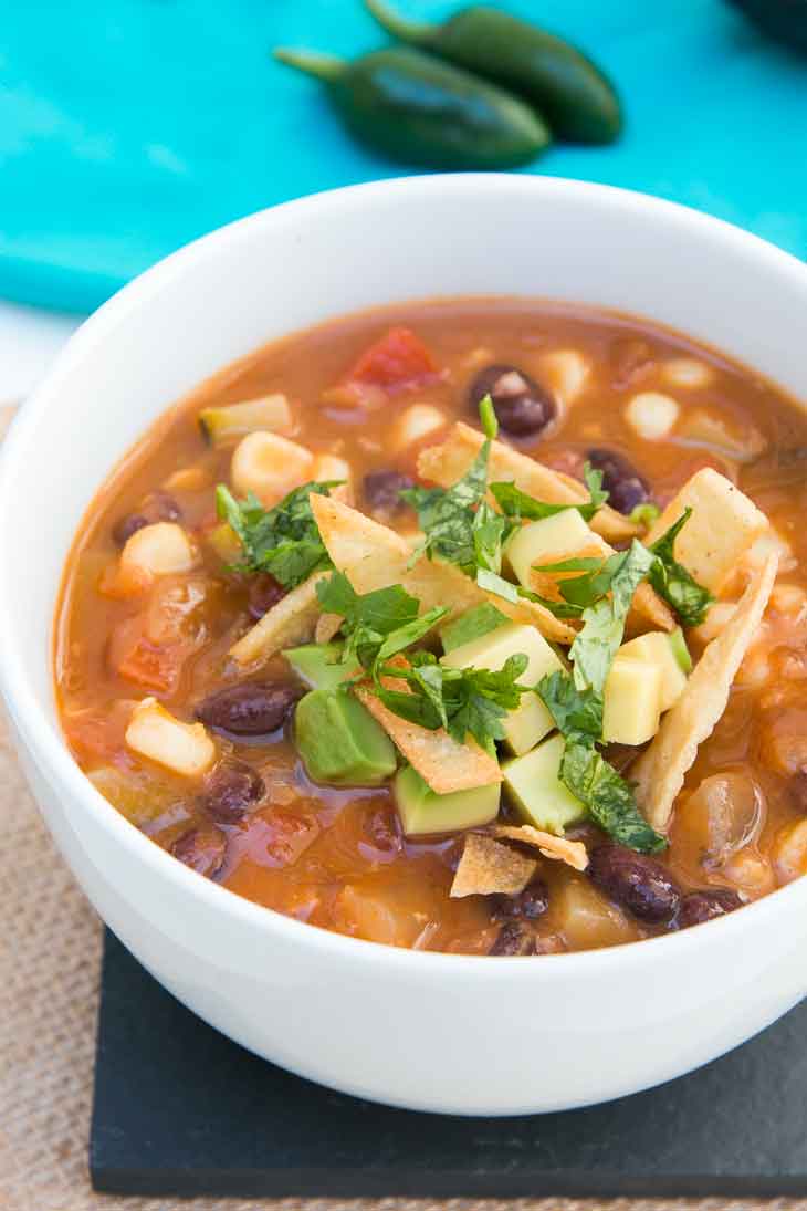 Second best vegan meal on VG in 2017. Loaded tortilla soup in a white bowl with jalapenos in the background. 