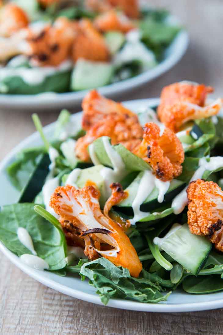 Best vegan meal on VG in 2017. Side photograph of a plated salad containing spinach, avocado, cucumber, and roasted buffalo cauliflower. 