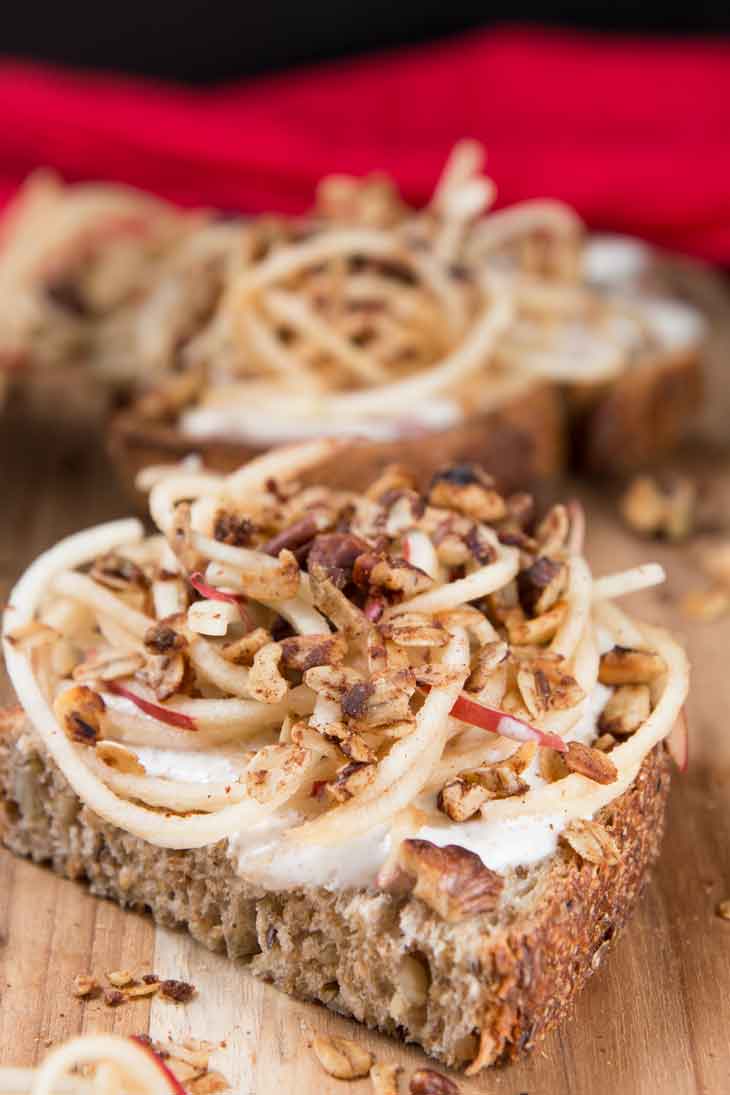 Photograph of vanilla yogurt cinnamon toast recipe topped with spiralized apples and granola. There's a red napkin in the background.