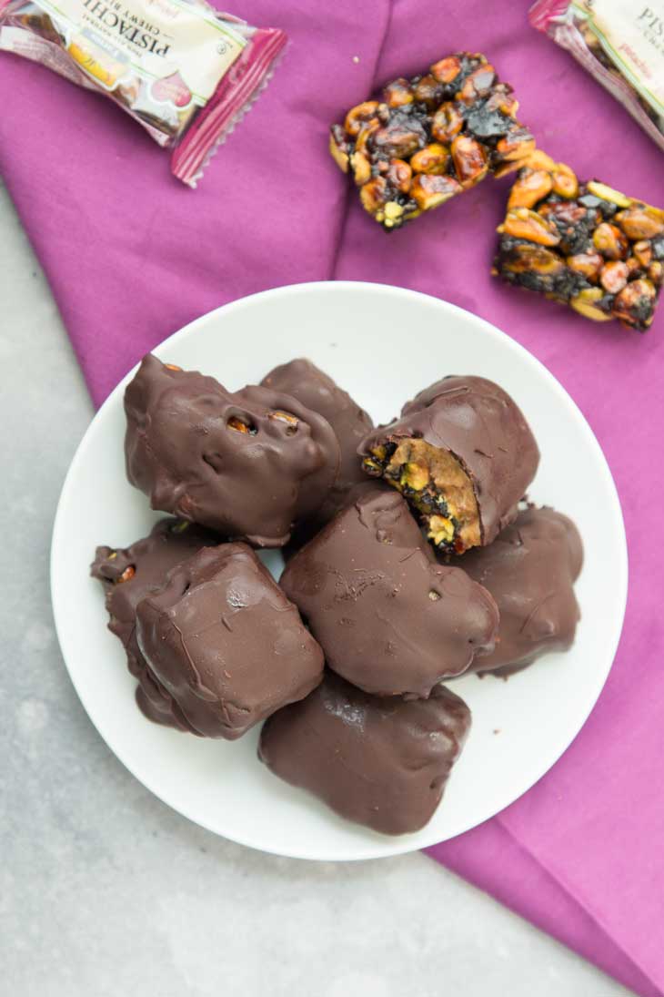 Overhead photograph of vegan chocolate bars covered with dark chocolate, sitting on a white plate with a purple napkin.