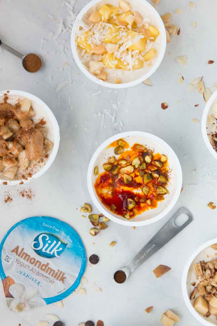 Overhead closeup of healthy yogurt cup combinations with ingredients scattered around. 