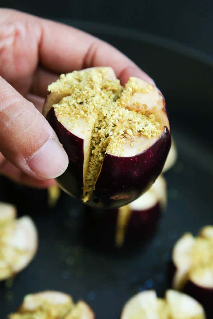 A hand holding an Indian stuffed baked eggplant