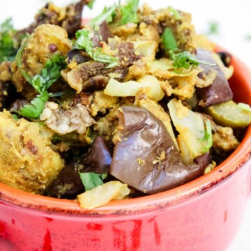 Indian stuffed baked eggplant and potatoes in a large red bowl