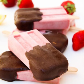 A close up of strawberry Popsicles on a white surface