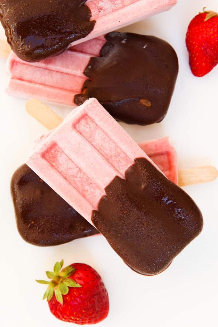 An overhead shot of strawberry Popsicle covered with chocolate 