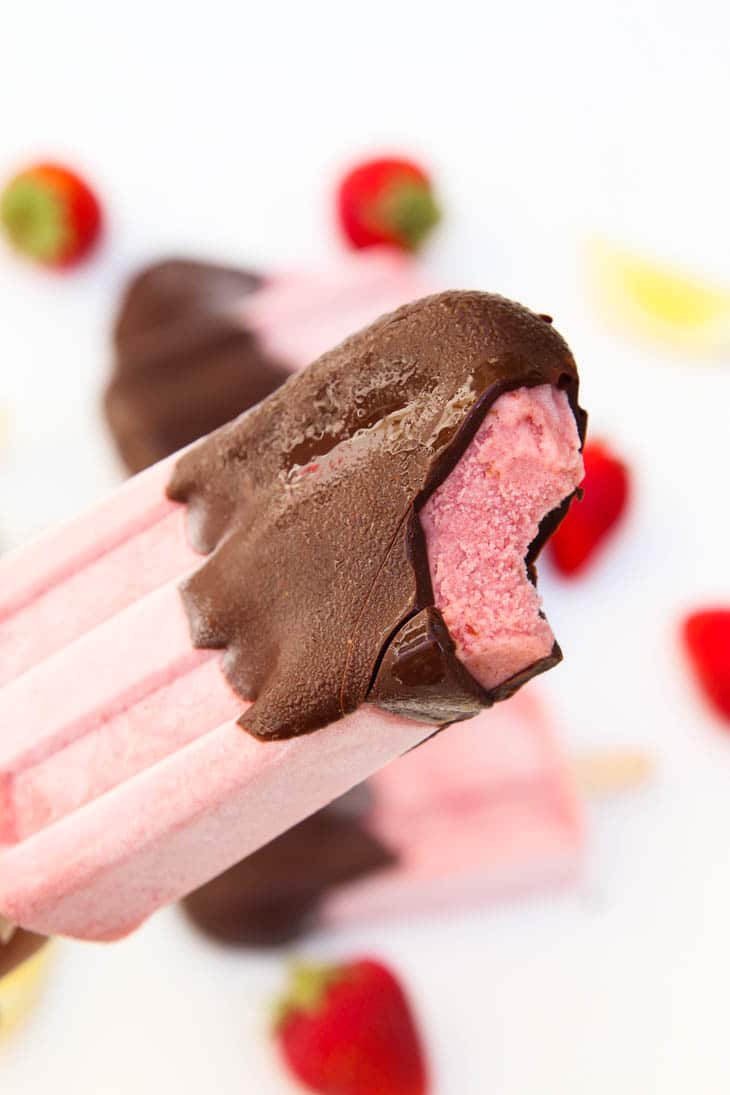 A close up of a strawberry Popsicle covered with chocolate