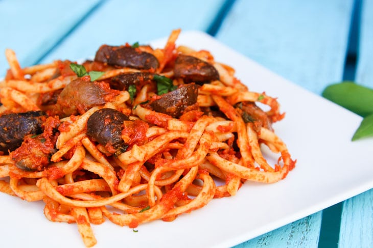 A close up of linguine with roasted mushrooms with a tomato sauce