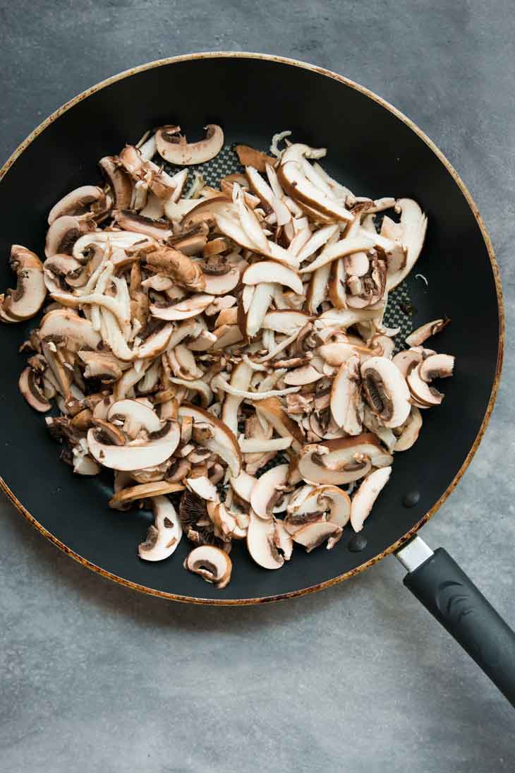 Shredded mushrooms cooking on a black non-stick pan for a bbq sandwich. 