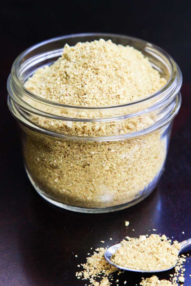 An Indian spice blend in a glass jar with a spoon