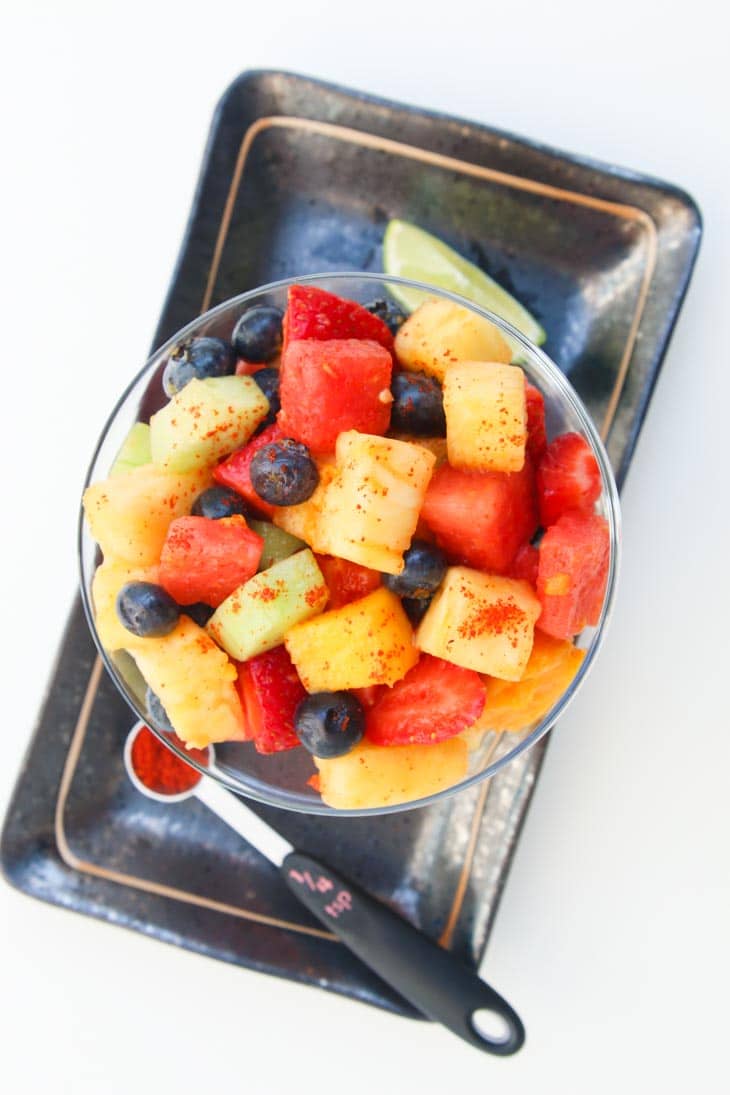 A homemade fruit salad in a large glass bowl sitting on a tray