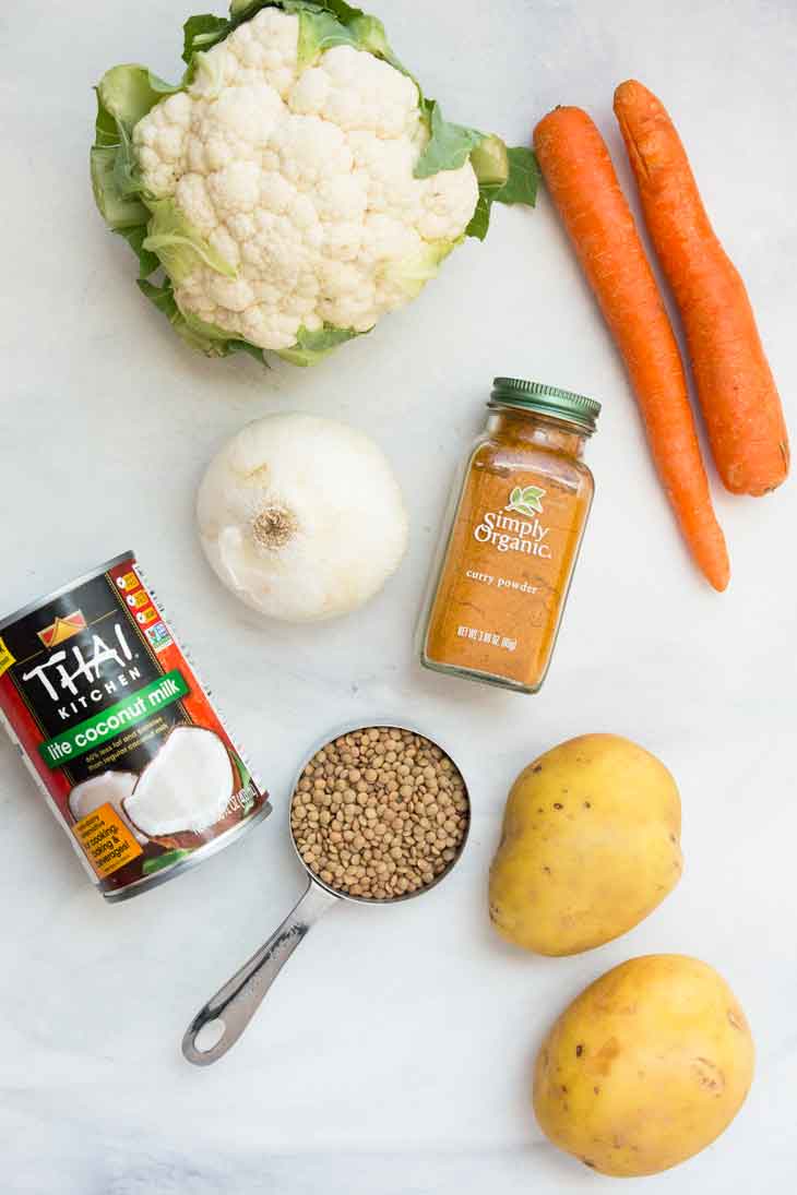 Photographie aérienne montrant les ingrédients nécessaires à la préparation d'une soupe aux lentilles végétalienne.