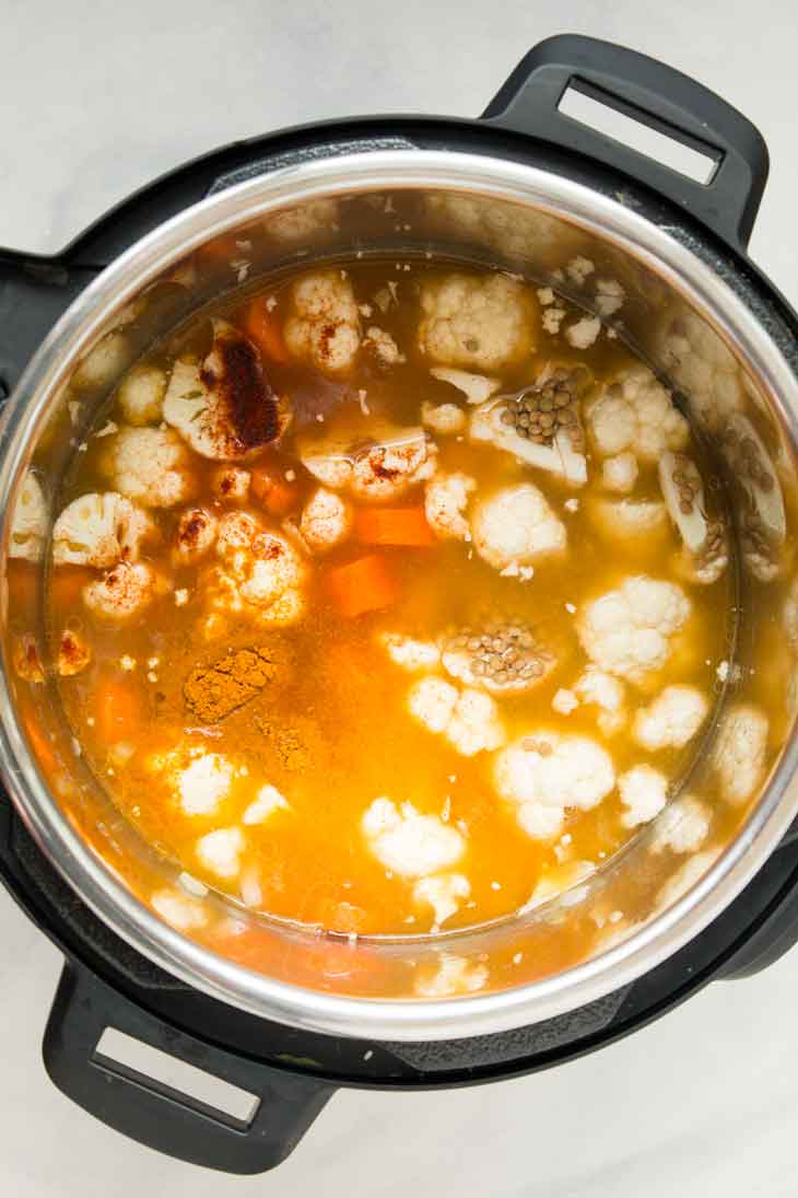 an overhead photograph of vegan lentil soup being made in the instant pot just before to pressure cooking.