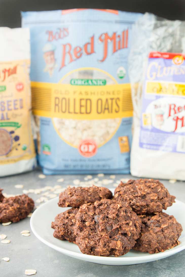 Side photograph of chocolate breakfast cookies on a white serving plate with bob's red mill products in the background.