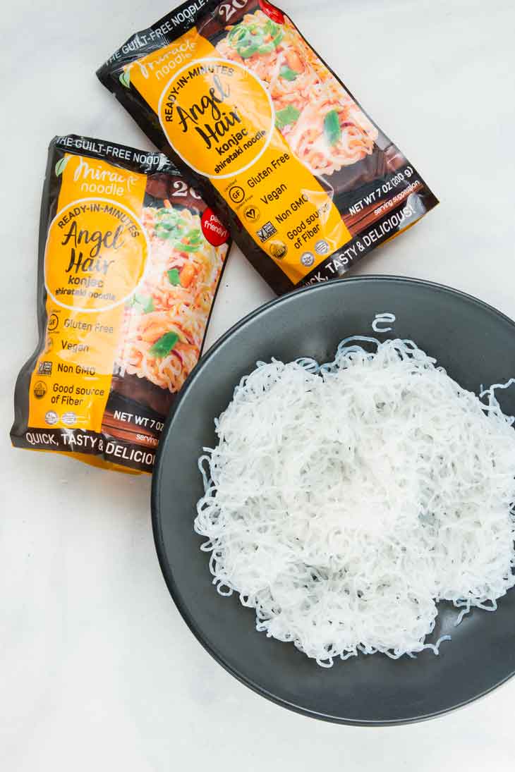 Overhead photograph of cooked miracle noodle angel hair in a bowl with packaging on the side.