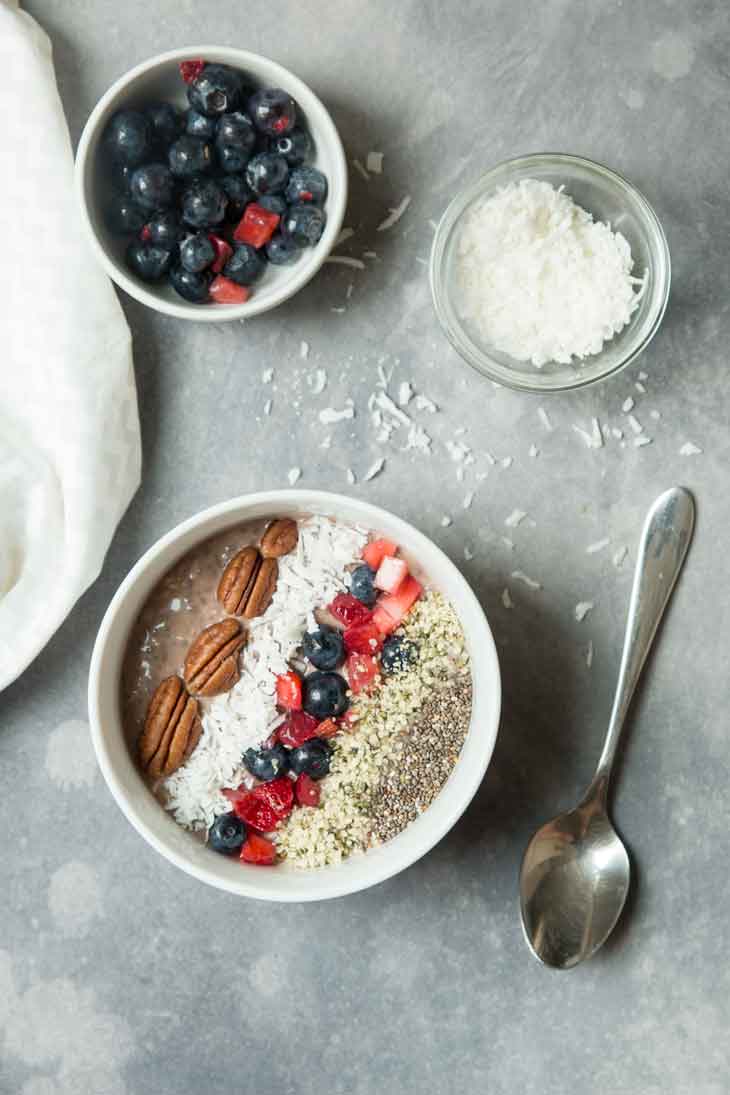 Overhead photograph of vegan keto superfood breakfast bowl with shredded coconut and mixed berries off to the side.