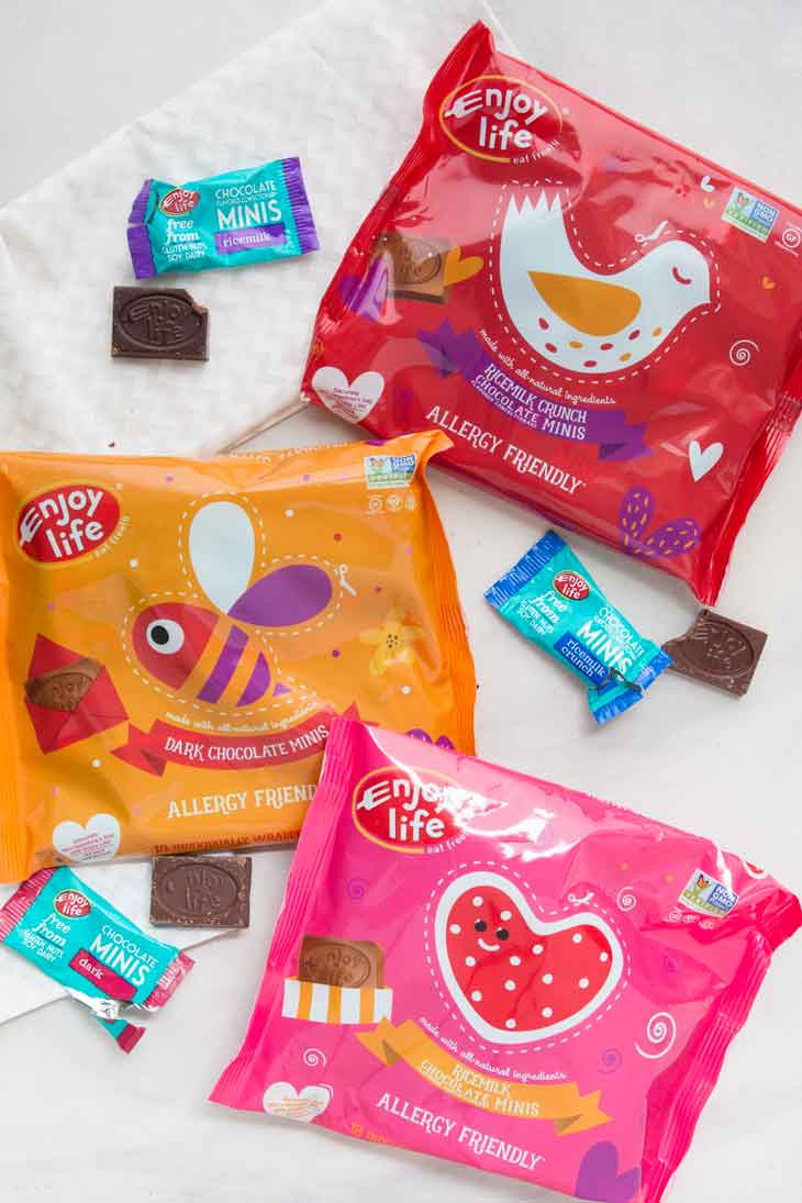 An overhead photograph of enjoy life foods valentines day mini chocolates. There are three different varieties and bags.