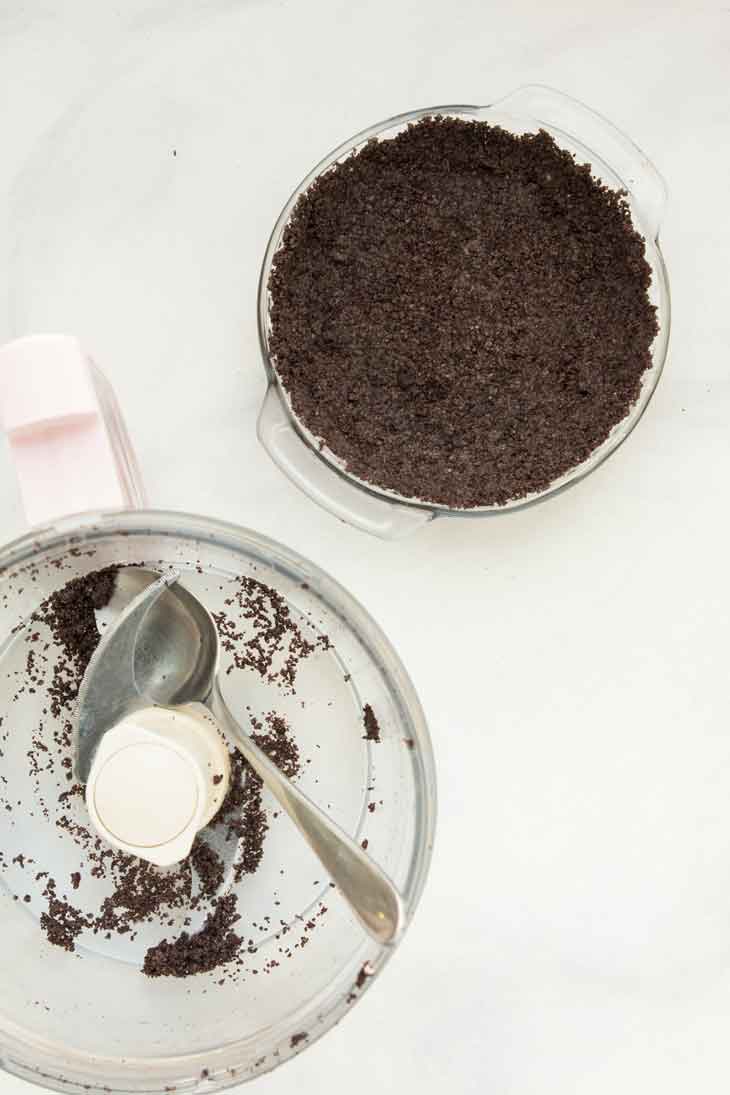 An overhead photograph of the pie being pressed into a mini pie dish for vegan chocolate pie.