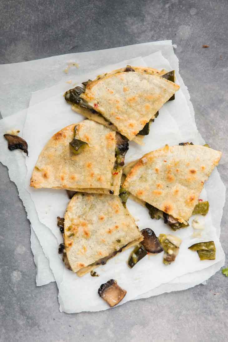 Overhead photograph of 4 pieces of vegan quesadilla sitting on parchment paper.