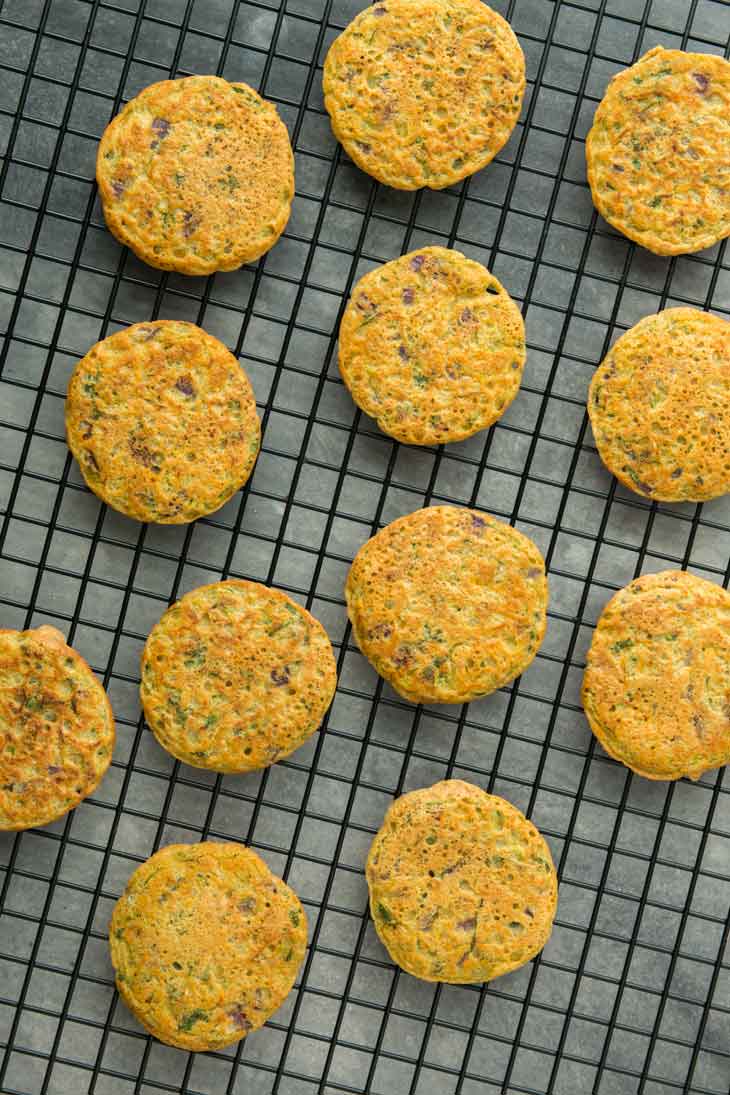 Ovehead photograph of several mini savory vegetable pancakes sitting on a cooling rack.